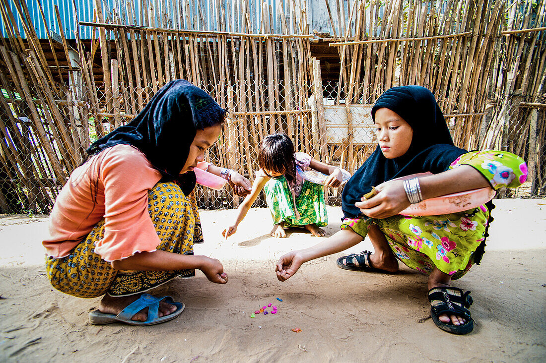 Cham-Kinder beim Spielen, Chau Doc, Vietnam. Letzter Tag im Mekong-Delta. Wir besuchten ein Dorf der Cham-Minderheit. Als diese Kinder merkten, dass wir ihre herzförmigen Waffeln nicht kaufen wollten, die uns laut einem Schild "cronic" geben würden, kehrten sie zu ihren Spielen zurück. An der kambodschanischen Grenze hatten wir viel Spaß, nachdem sich unsere Gruppe auf Anweisung geweigert hatte, den vom Grenzbeamten verlangten zusätzlichen Dollar zu bezahlen. Kein glücklicher Mann...