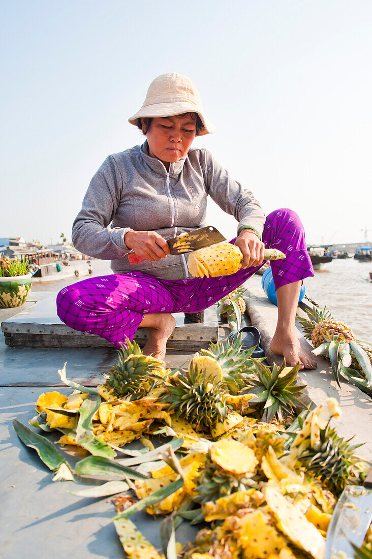 Ananas-Verkaufsboot auf dem schwimmenden Markt von Can Tho, Mekong-Delta, Vietnam. Auf dem schwimmenden Markt von Can Tho herrscht ein reges Treiben. Auf den Booten stapeln sich die Früchte, und die Markthändler verkaufen sowohl untereinander als auch an die vorbeifahrenden Touristen. Es gibt unzählige schwimmende Märkte im Mekong-Delta, aber Can Tho ist einer der größten mit Hunderten von Booten, die sich jeden Morgen aneinander vorbeidrängen, bevor sie sich am nächsten Tag wieder auf den Markt vorbereiten. Jedes Boot hängt ein Exemplar seiner Waren oben auf, damit die Passanten wissen, was s