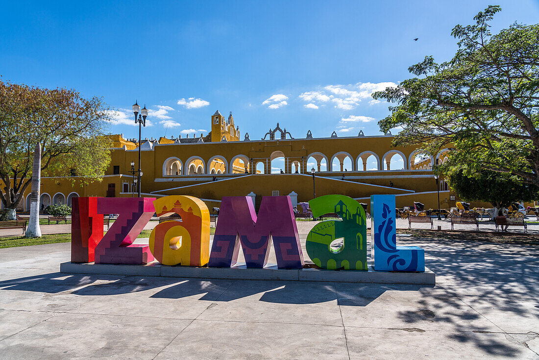 The colorful town sign of Izamal, Yucatan, Mexico, known as the Yellow Town. The Historical City of Izamal is a UNESCO World Heritage Site. Behind is the Convent of San Antonio.