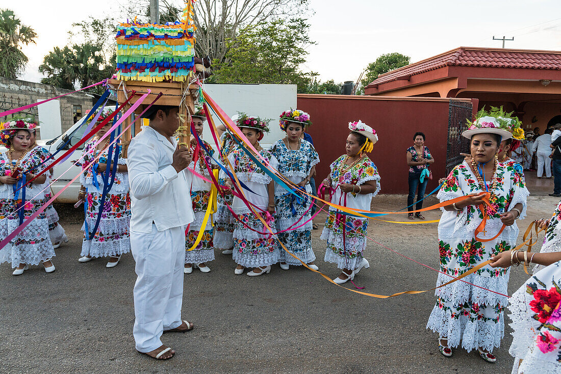 Frauen in traditionellen, festlich bestickten Huipils und geblümten Hüten bereiten sich auf den Tanz des Schweinekopfes und des Truthahns oder Baile de la cabeza del cochino y del pavo in Santa Eleana, Yucatan, Mexiko, vor. Dieser Festtanz der Maya wird nur einmal im Jahr aufgeführt.