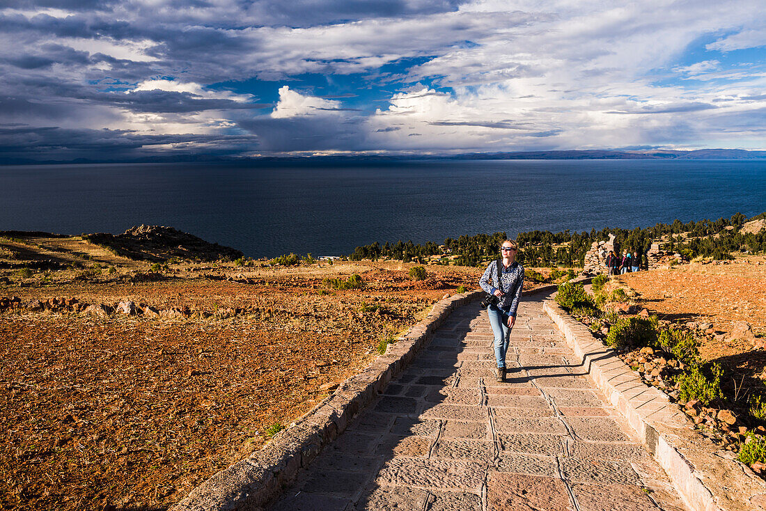 Woman walking on Inca path on Amantani Islands (Isla Amantani), Lake Titicaca, Peru