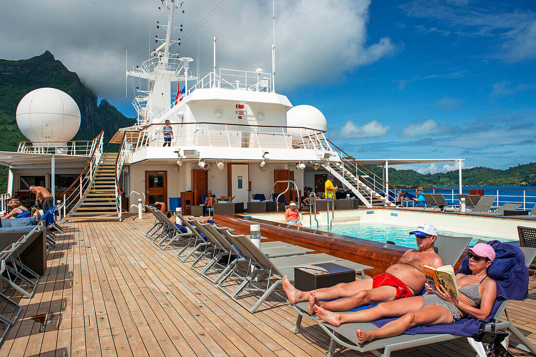 Paul Gauguin Kreuzfahrtschiff, Passagiere entspannen sich auf dem Oberdeck im Swimmingpool. Gesellschaftsinseln, Französisch-Polynesien, Südpazifik.