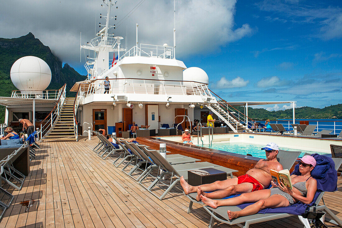 Paul Gauguin cruise ship, passengers relaxing in the upper deck in the swimming pool. Society Islands, French Polynesia, South Pacific.