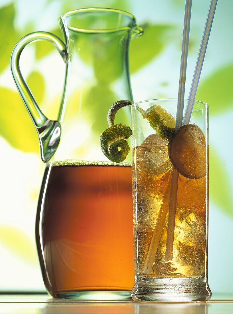 Iced tea in carafe & glass with ice cubes & limes