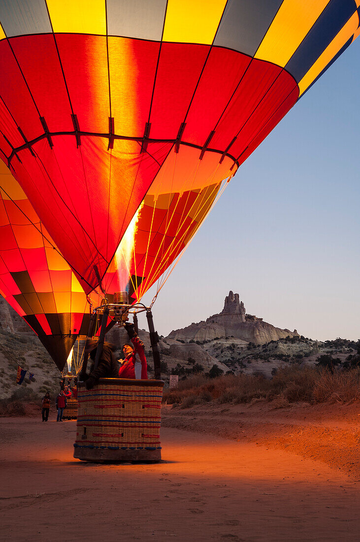 Hot Air balloons at dawn glow with Church Rock in background; 25th Annual Red Rock Balloon Rally at Red Rock State Park, Gallup, New Mexico.