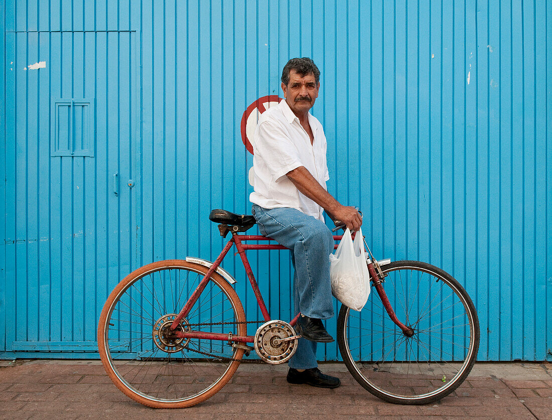 Man on bicycle in front of blue wall, Tonal?, Mexico.