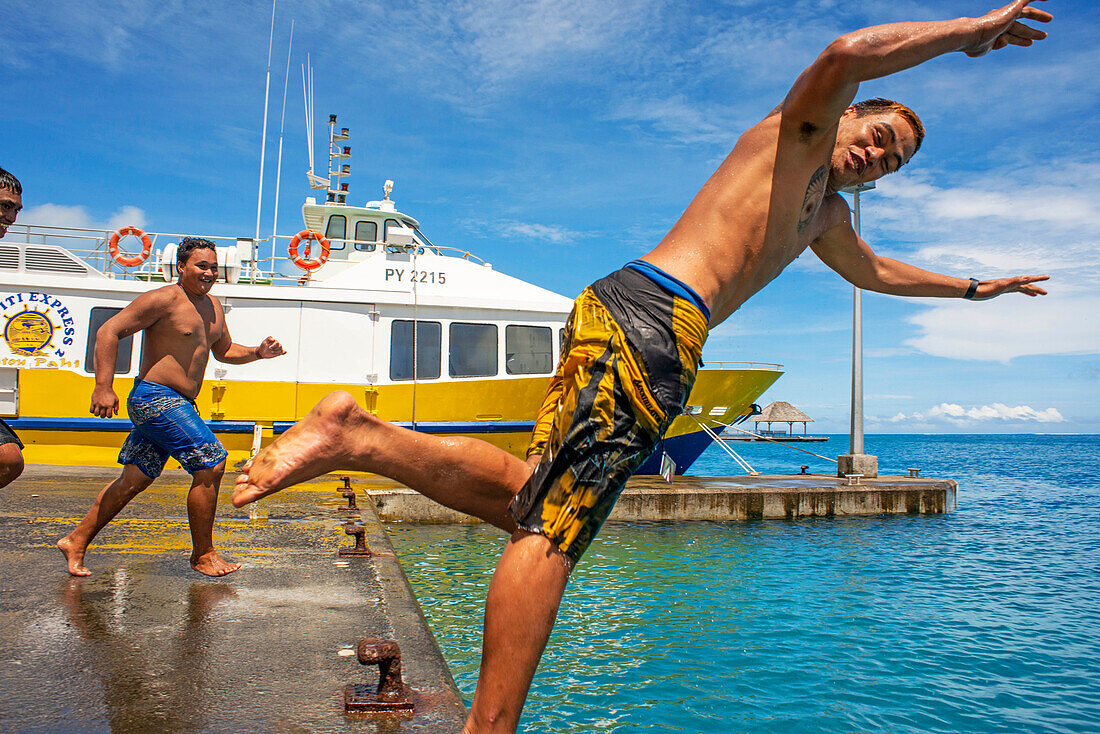 Jugendliche beim Sprung ins Wasser neben der Anlegestelle von Bora Bora Vaitape, Gesellschaftsinseln, Französisch-Polynesien, Südpazifik.