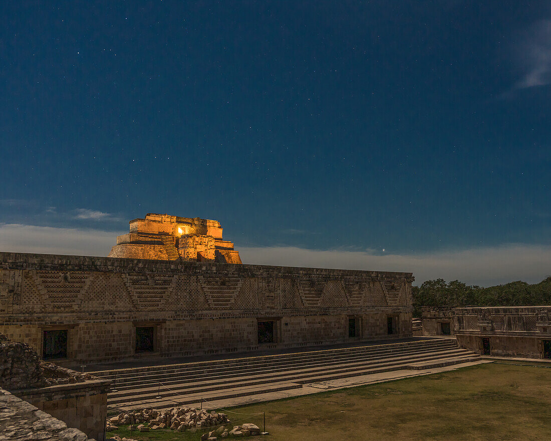 Die Pyramide des Magiers hinter dem Ostgebäude des Nonnenklosters in den prähispanischen Maya-Ruinen von Uxmal, Mexiko, ist beleuchtet.