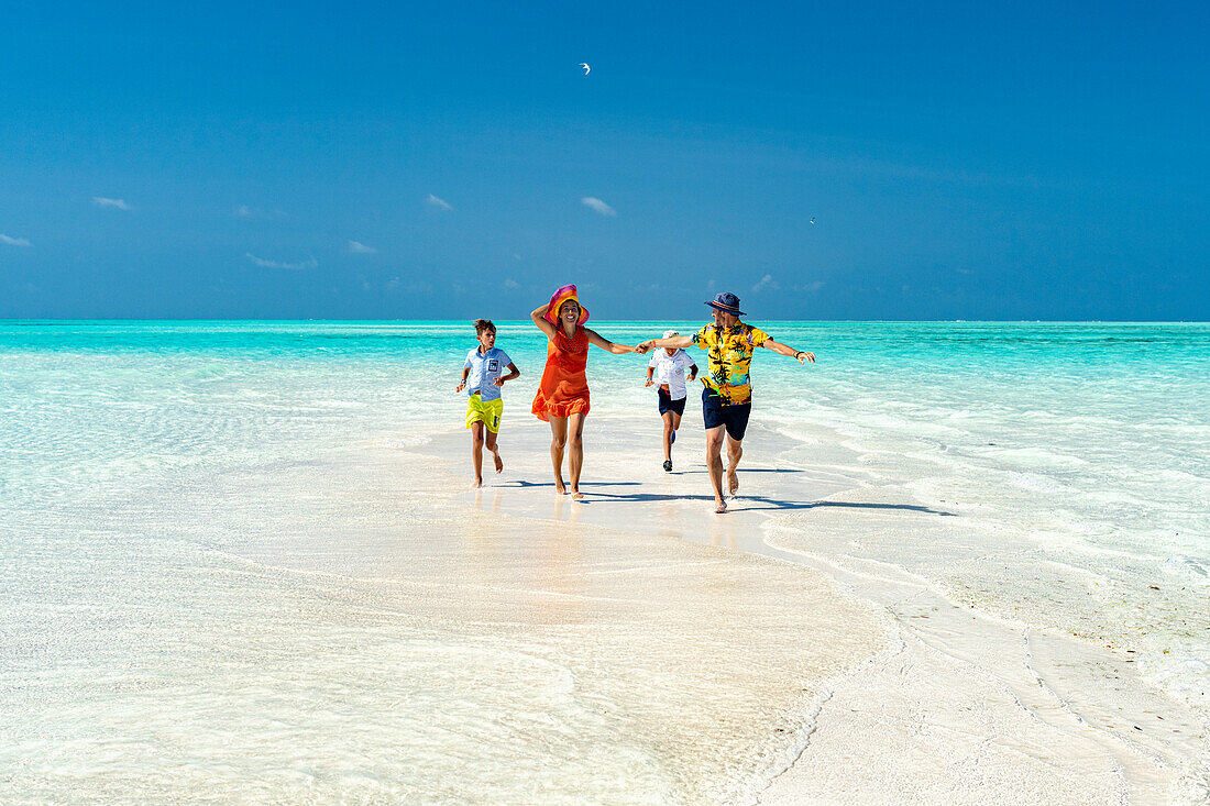 Familie mit zwei Jungen, die zusammen an einem idyllischen Strand rennen, Sansibar, Tansania, Ostafrika, Afrika