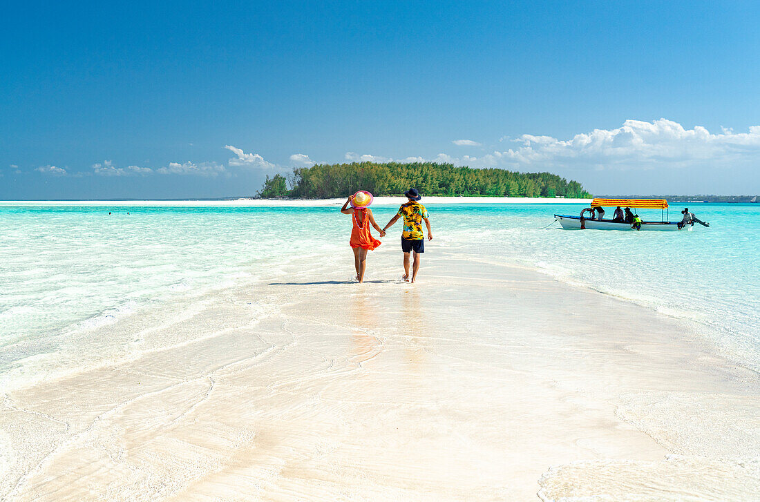 Man and woman in love holding hands walking on empty sandy shore surrounded by the Indian Ocean, Zanzibar, Tanzania, East Africa, Africa
