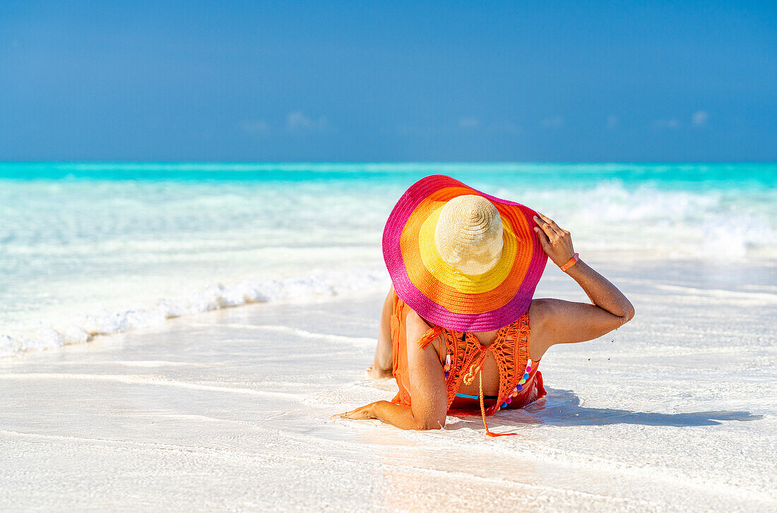 Frau mit Hut entspannt am idyllischen, leeren Strand, Sansibar, Tansania, Ostafrika, Afrika