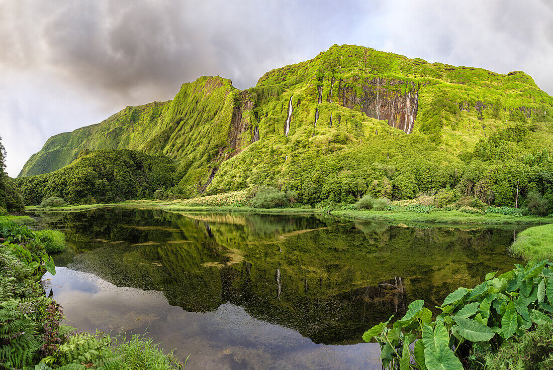 Panorama shot of Poco da Ribeira do Ferreiro lake and waterfall with a side of the mountains covered by flowers and vegetation, Flores island, Azores Islands, Portugal, Atlantic Ocean, Europe