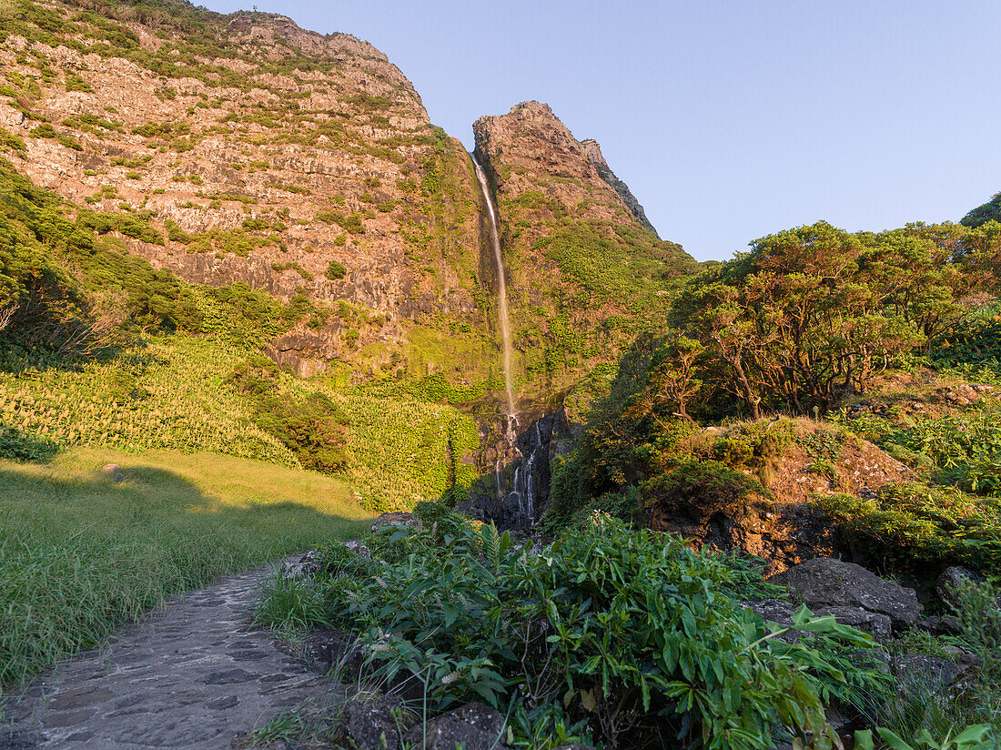 Waterfall, Poco do Bacalhau, at sunset on Flores island, Azores Islands, Portugal, Atlantic Ocean, Europe