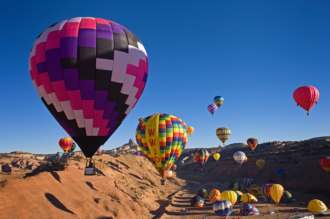 25. jährliche Red Rock Balloon Rally im Red Rock State Park, Gallup, New Mexico. Frühmorgendlicher Massenballonaufstieg mit Church Rock in der Ferne.