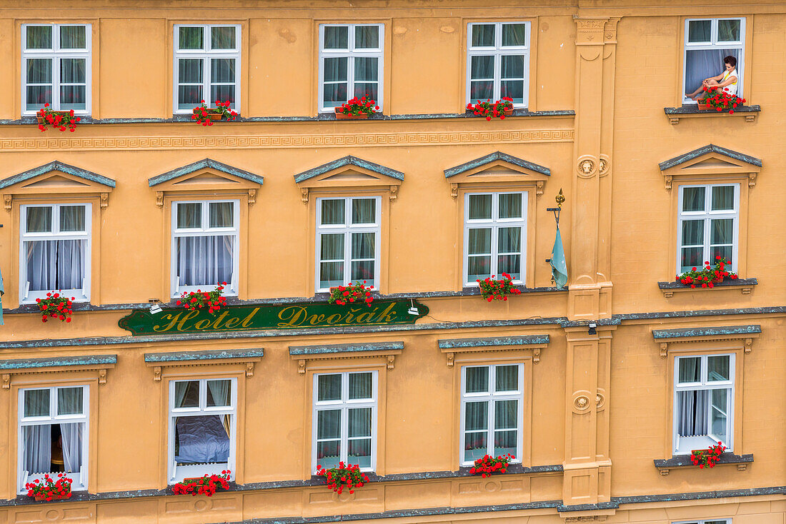 Frau sitzt im Fenster eines Hauses im historischen Zentrum von Cesky Krumlov, UNESCO-Weltkulturerbe, Cesky Krumlov, Südböhmische Region, Tschechische Republik (Tschechien), Europa