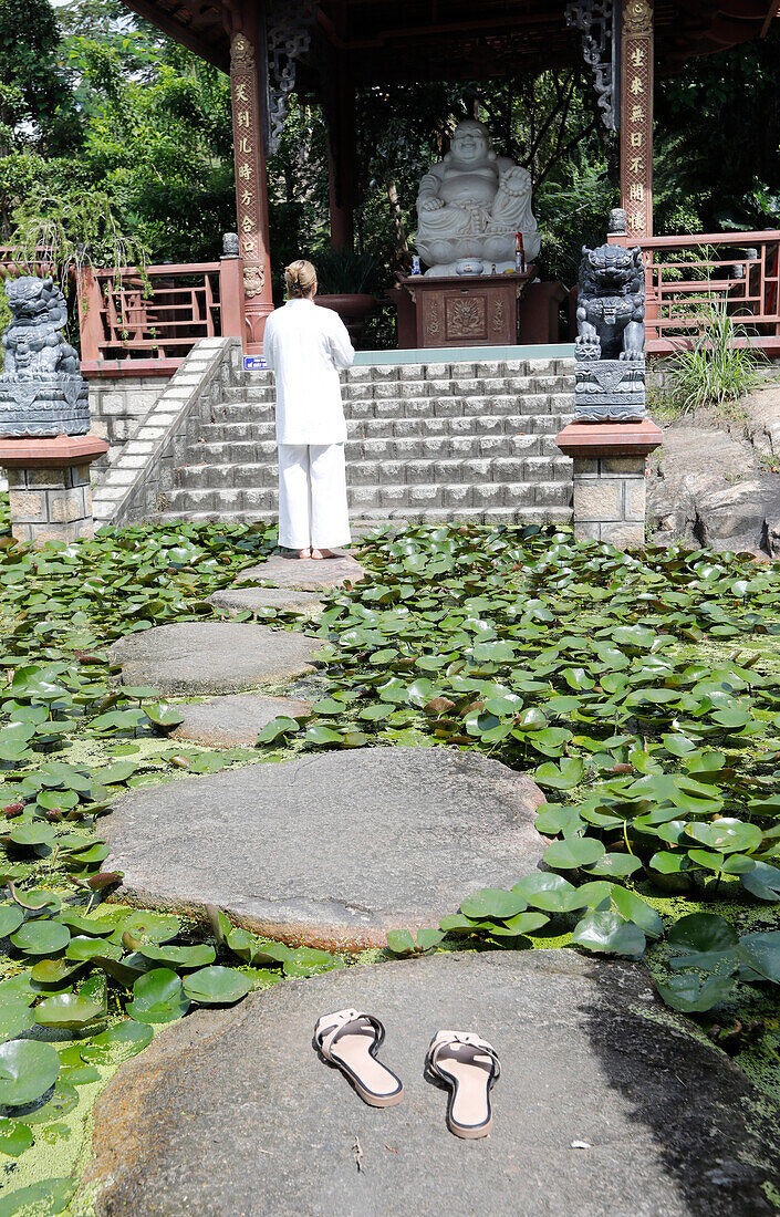 Buddhist woman, Phat Quang Buddhist temple, temple pond with stones and water lilies, Doc, Vietnam, Indochina, Southeast Asia, Asia
