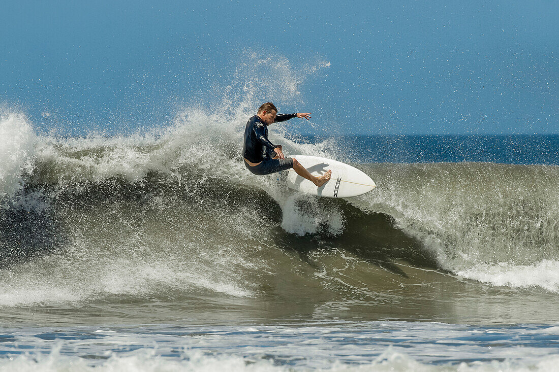 Shortboard surfer rides a wave at this fast-growing surf beach and yoga destination, Playa Guiones, Nosara, Guanacaste, Costa Rica, Central America