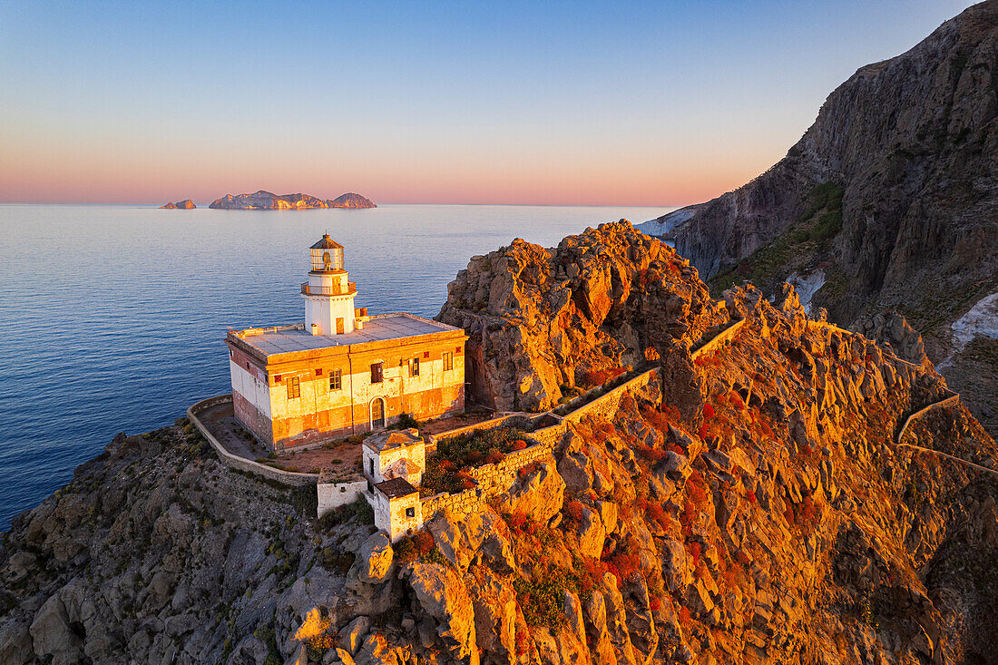 Aerial view of Punta della Guardia lighthouse on top of a cliff on the island of Ponza, lit from sunrise, Ponza island, Pontine islands, Mediterranean Sea, Latium, Lazio, Italy, Europe