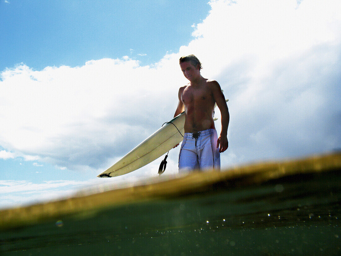 Surfer, der sein Brett ins Meer trägt, geteilte Ebene