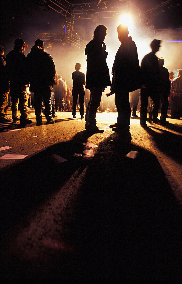 Clubber stehen am Ende der Nacht in Silhouette auf der Straße