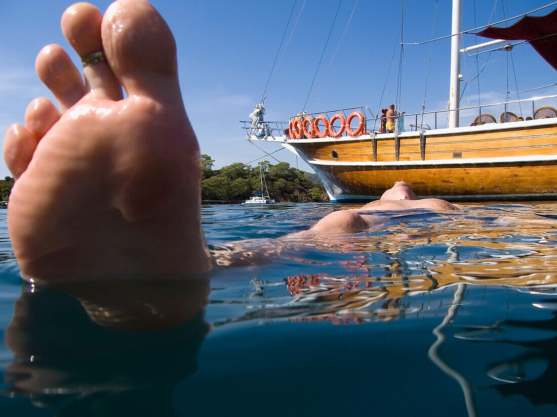 Männlicher Schwimmer, der neben einem vertäuten Boot schwimmt, Tiefblick