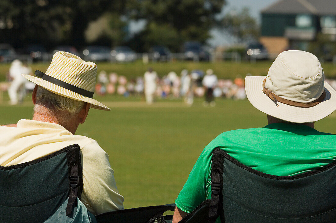 Rear View Of Spectators Watching A Cricket Match On A Hot Summers Day At Hastings.