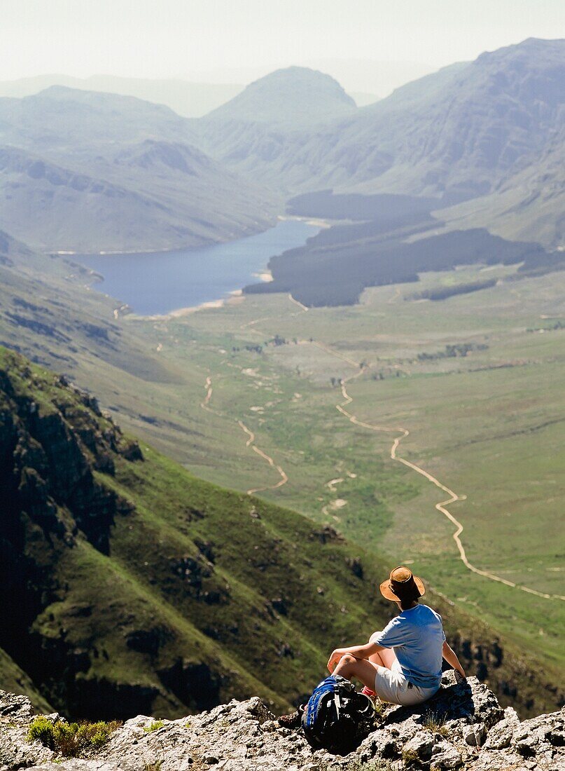 Wanderer mit Blick auf die Aussicht, auf dem Gipfel eines Berges sitzend, Rückansicht