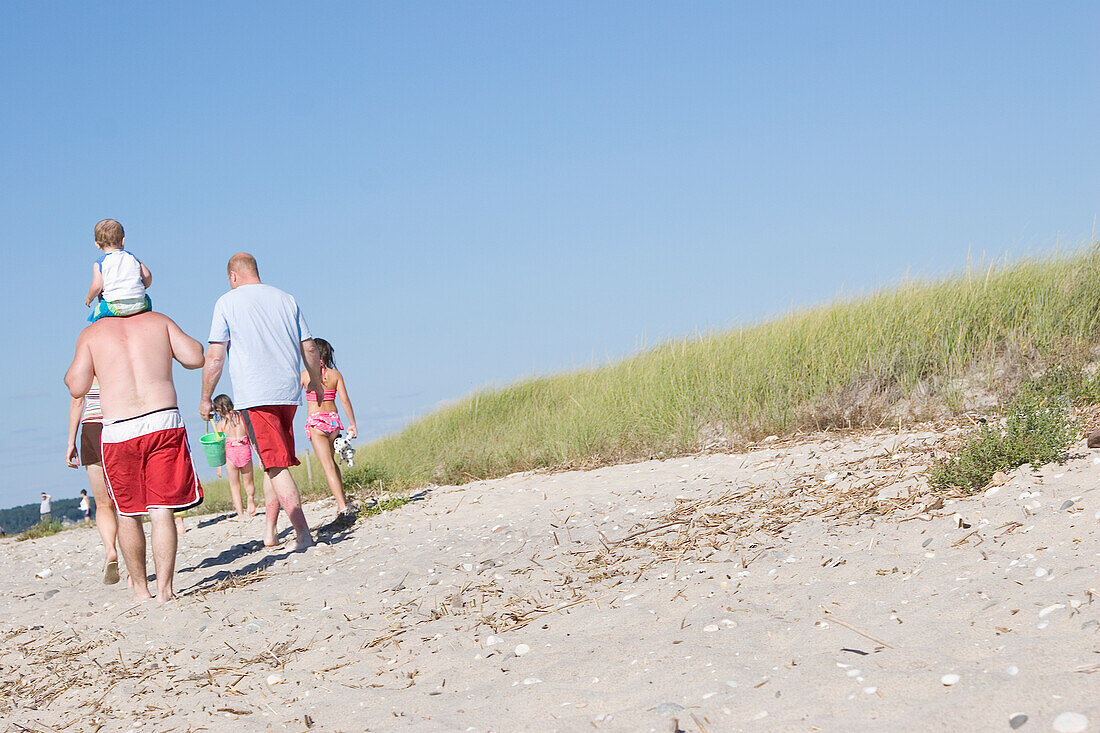 Familie bei einem Spaziergang durch die grasbewachsenen Sanddünen am Strand