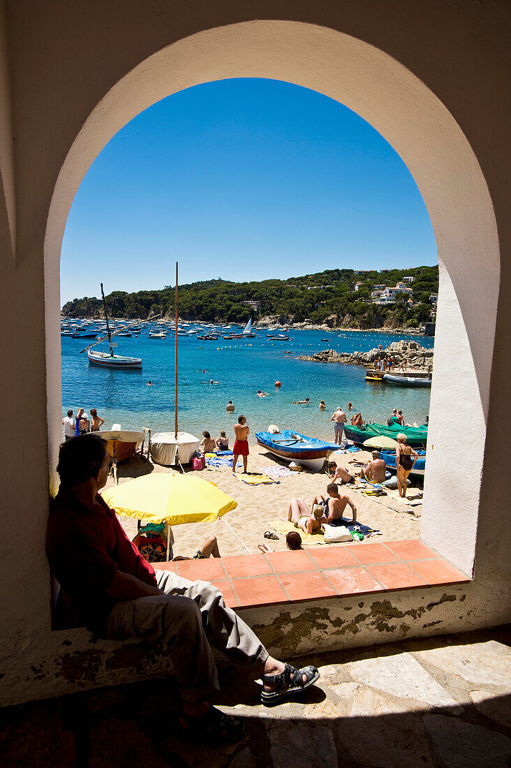 Person Sitting Under Arch Near Beach In Calella Fishing Village