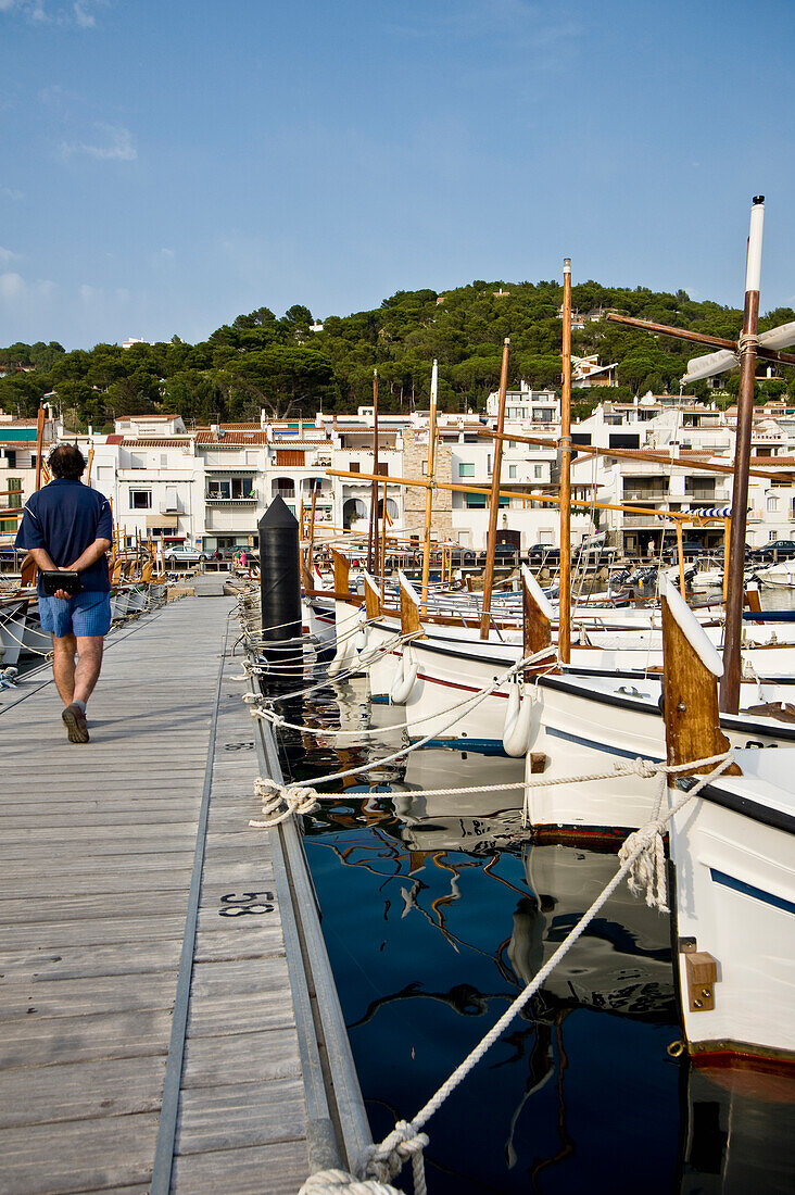 Man Passing Boats In Fishermen Village Port De La Selva