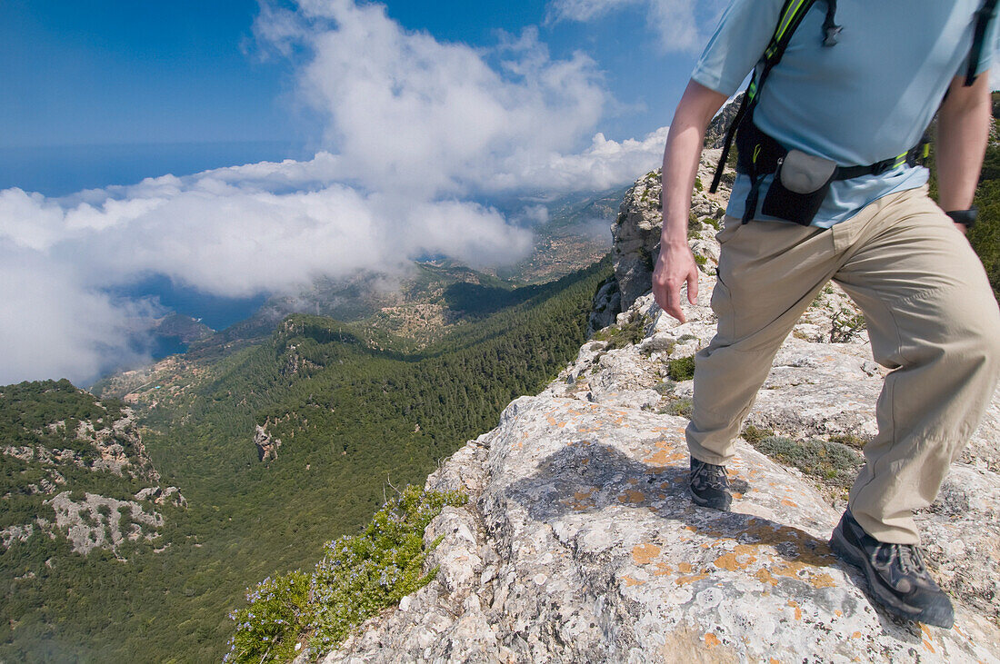 Wanderer, der neben einer Klippe auf dem Bergpfad geht, Tiefblick