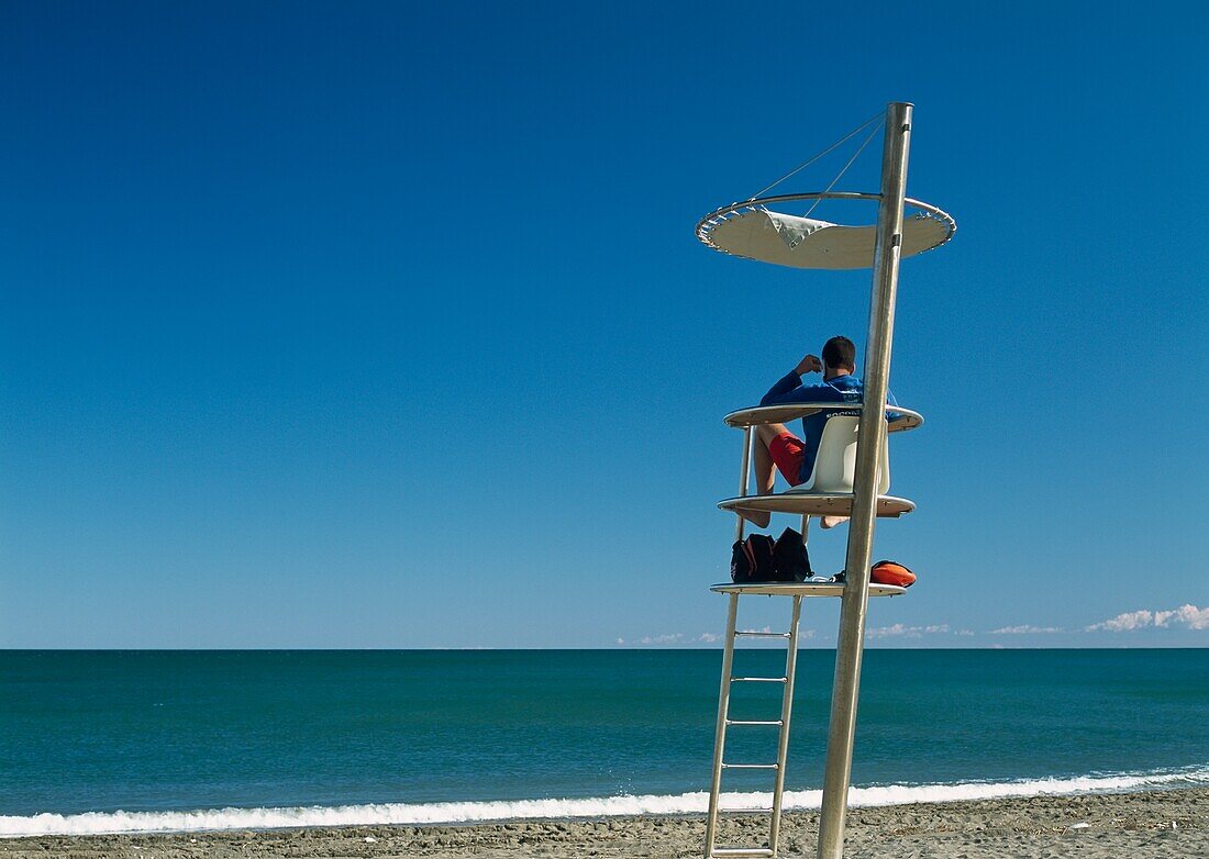 Lifeguard Sitting At Tower On Beach