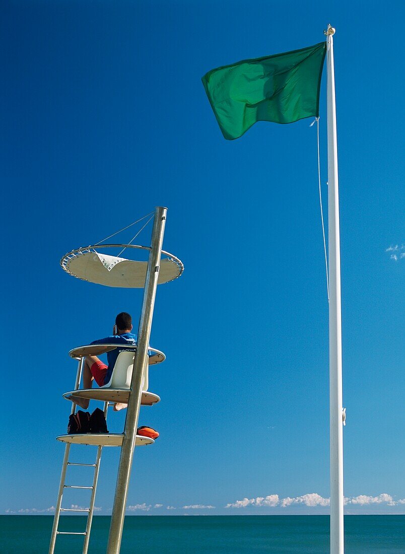 Lifeguard Sitting At Tower On Beach
