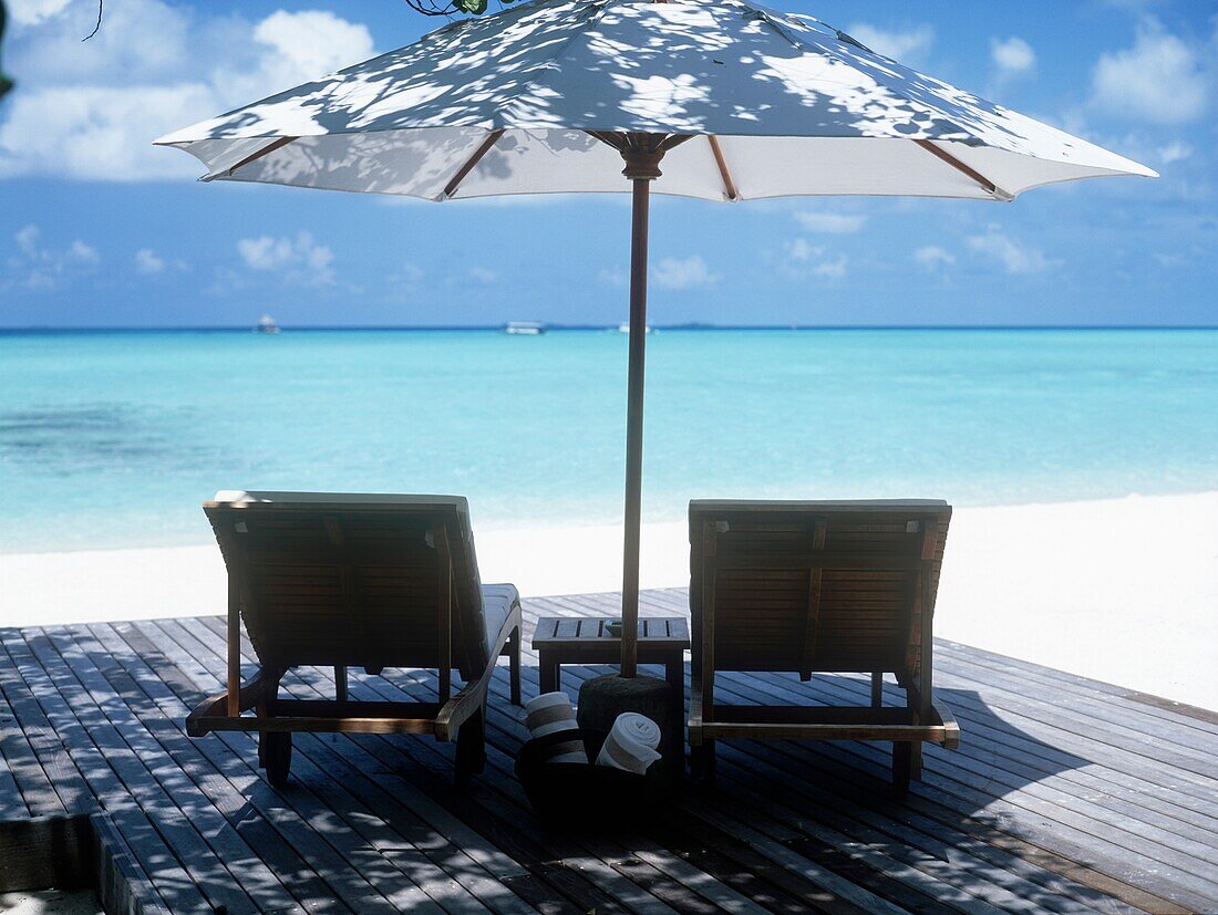 Deck mit Stühlen und Sonnenschirm mit Blick auf das Meer