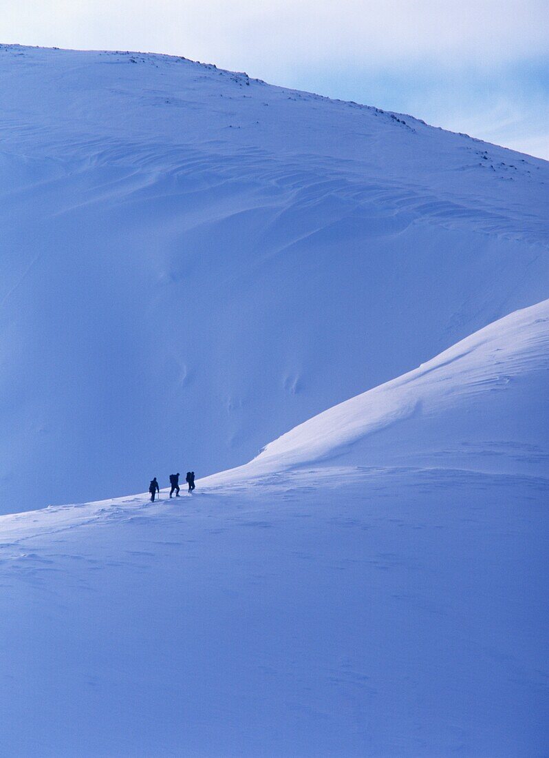 Silhouetten von Wanderern beim Klettern am Bergkamm