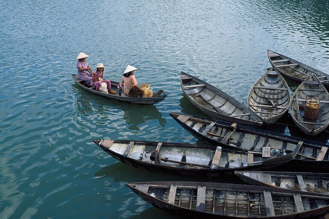 Three Women In Boat Wearing Conical Hats