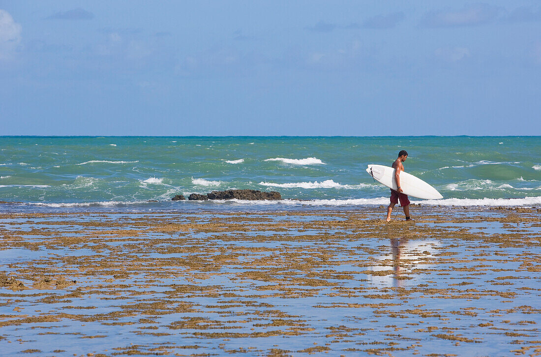 Man Carrying Surfboard At Praia Do Forte, Bahia,Brazil