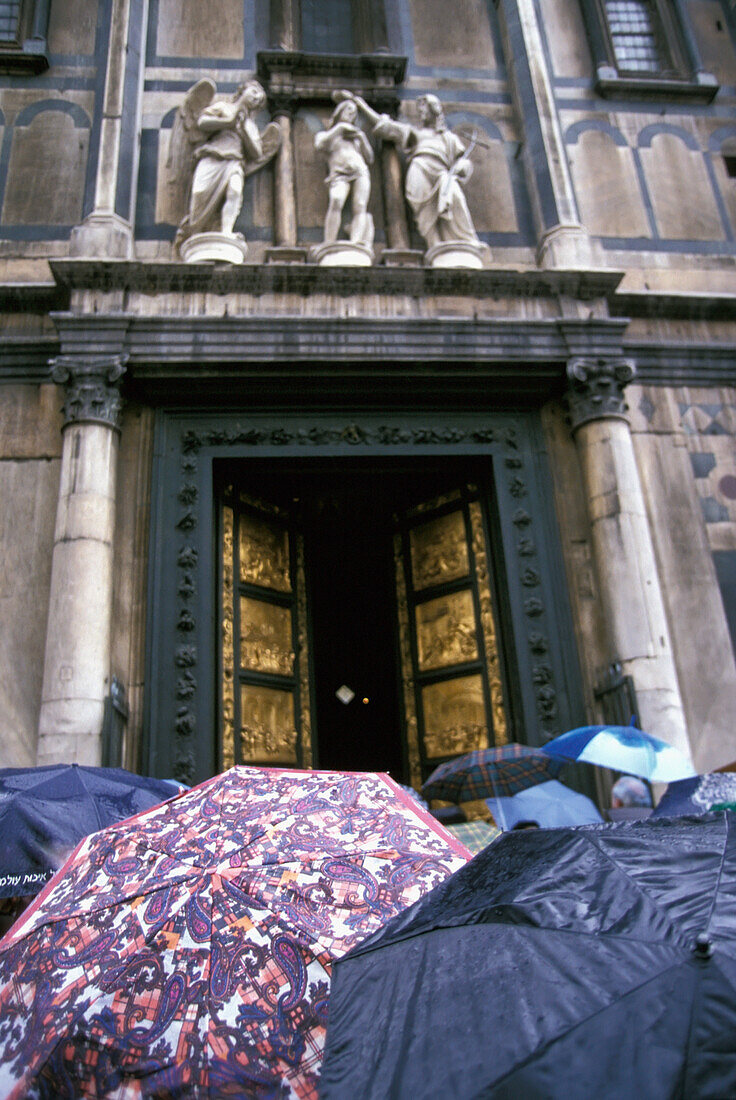 Menschen unter Regenschirmen außerhalb des Doms