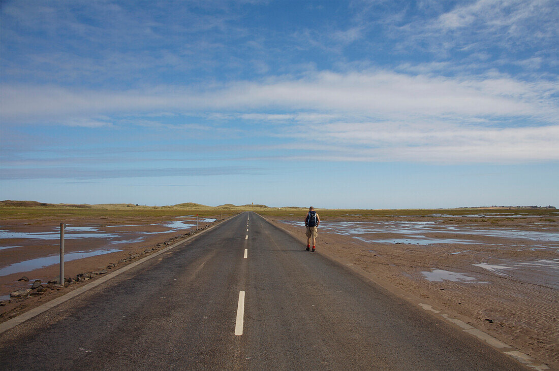 Person Walking Along Road In Lindisfarne, England,Uk