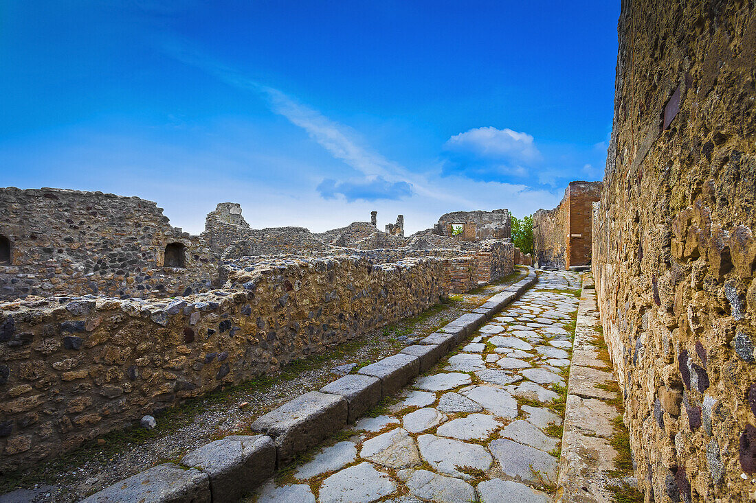 Ein steinerner Pfad, der neben den Ruinen von Mauern verläuft; Pompei, Kampanien, Italien