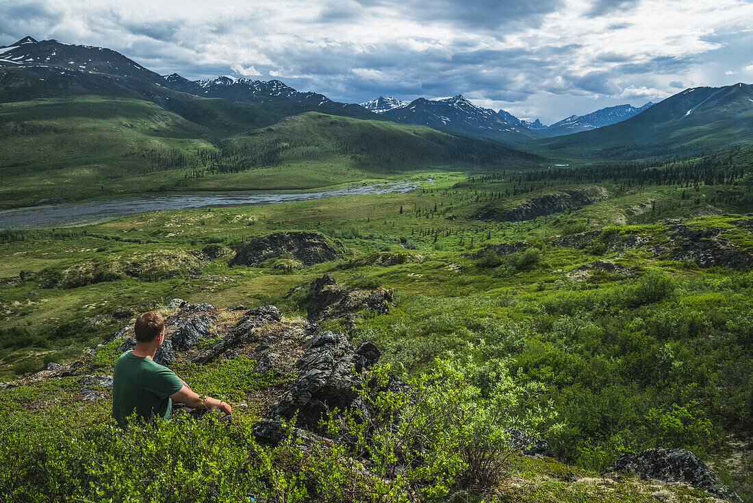 Mann sitzt mit Blick auf das Klondike-Tal entlang des Dempster Highway; Yukon, Kanada