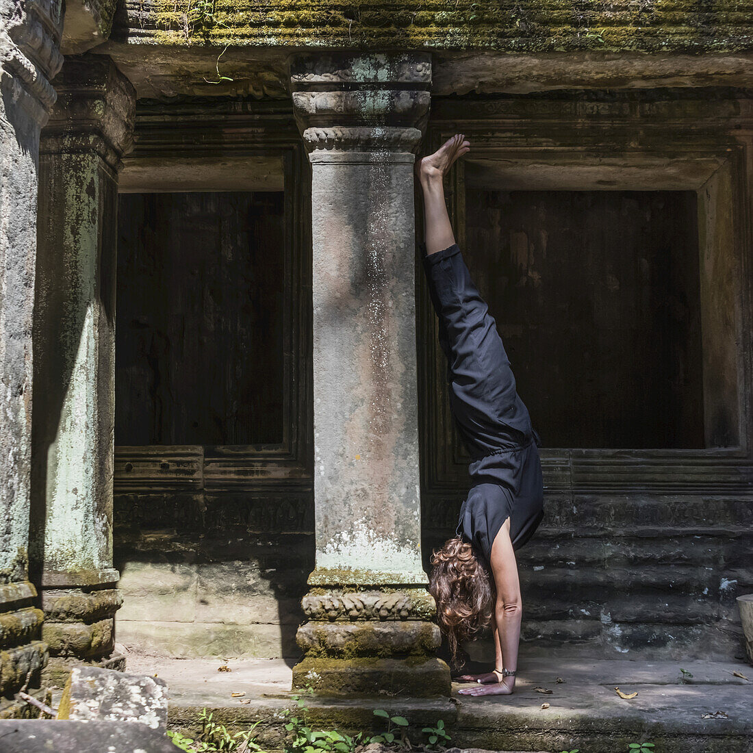 Eine Frau macht einen Handstand am Ta-Prohm-Tempel; Krong Siem Reap, Provinz Siem Reap, Kambodscha