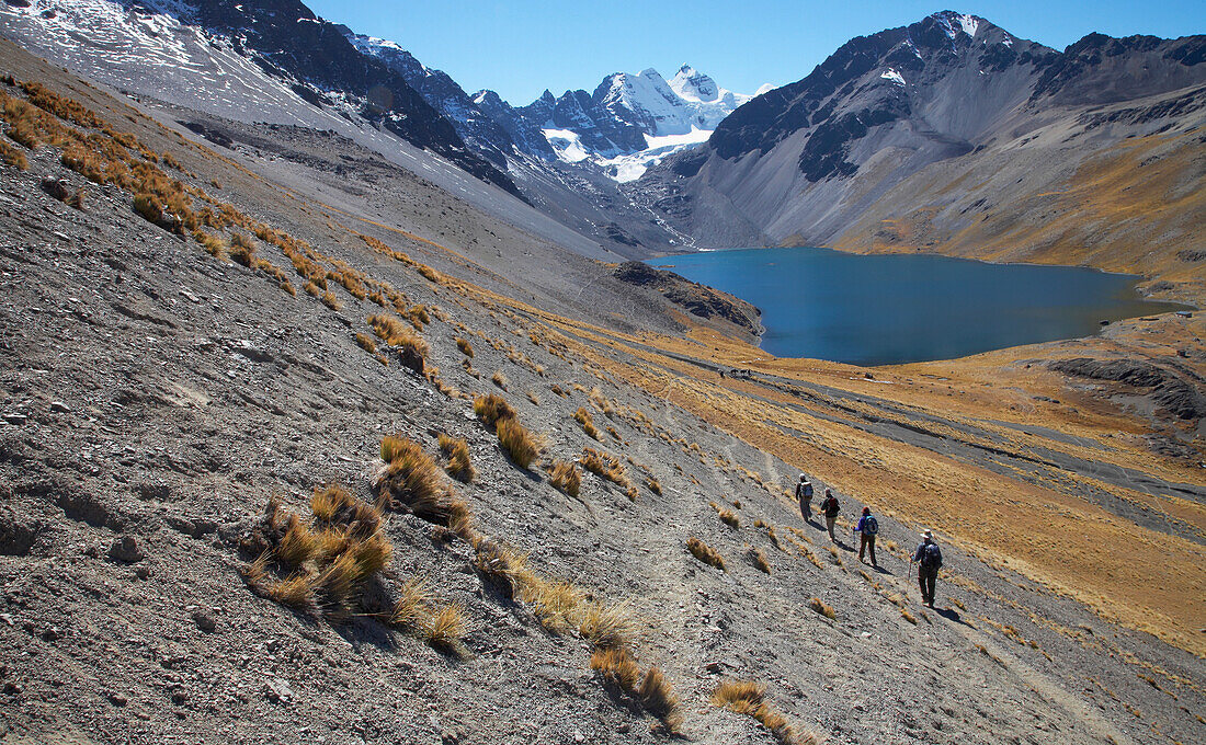 Trekkers Walking Down To Glacial Lake