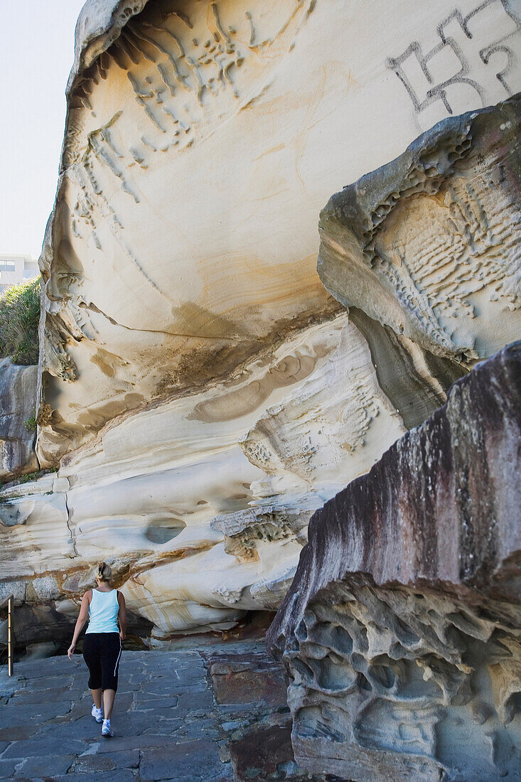 Woman Walking Past Cliff