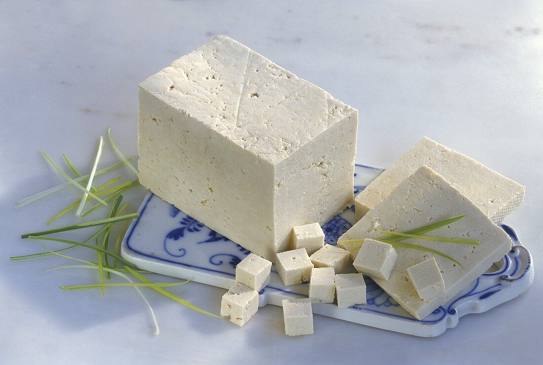 A piece of tofu, tofu slices and cubes