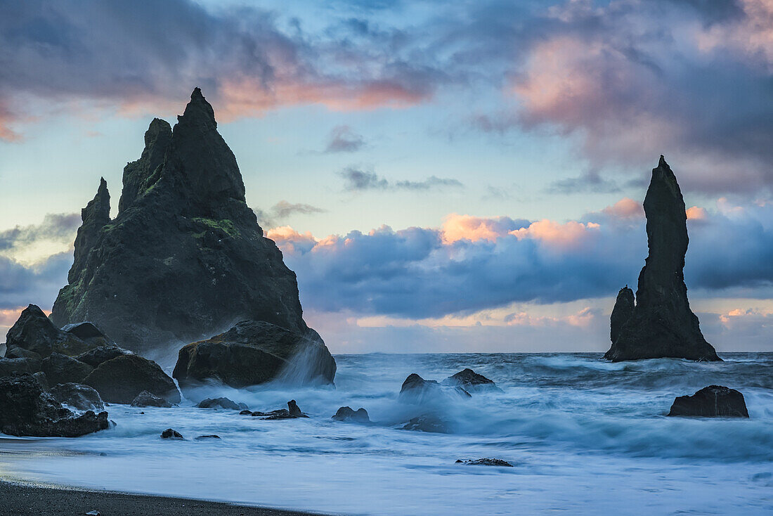 Die als Reynisdrangar bekannten Seeberge mit Wellen und Sonnenaufgang über ihnen, Südküste; Island