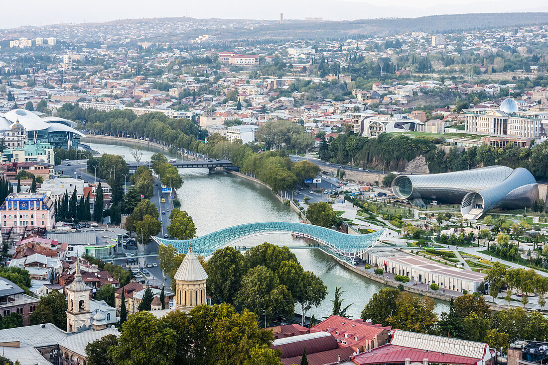 Tiflis, die Hauptstadt und größte Stadt Georgiens, mit der Friedensbrücke, dem röhrenförmigen Konzertsaalgebäude und dem pilzförmigen Justizgebäude; Tiflis, Georgien.