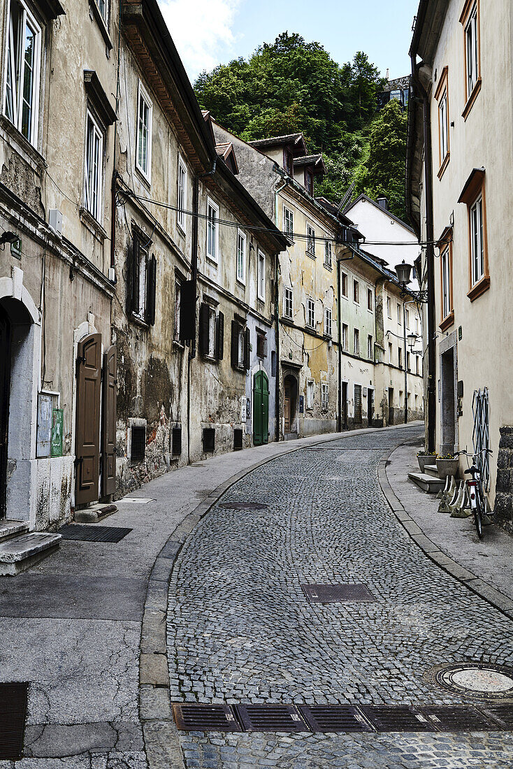 Eine Kopfsteinpflaster-Gasse verläuft zwischen Wohngebäuden; Slowenien