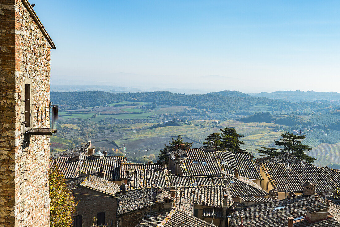 Panoramablick auf bunte Felder in der Toskana mit blauem Himmel und Ziegeldächern der Stadt Montepulciano; Toskana, Italien
