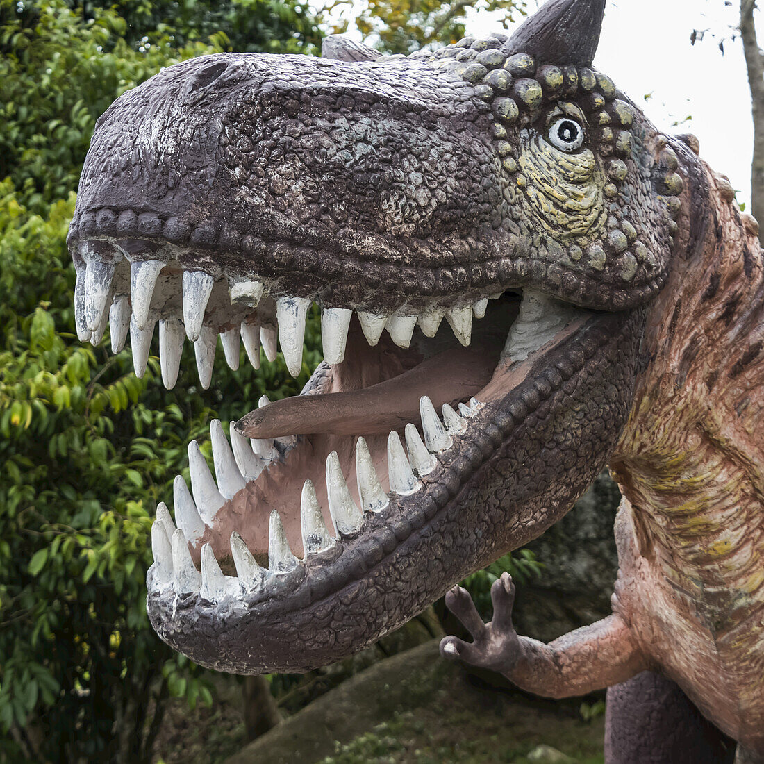 Skulptur eines Dinosauriers mit weit geöffnetem Maul, das seine Zähne zeigt; Ko Samui, Chang Wat Surat Thani, Thailand